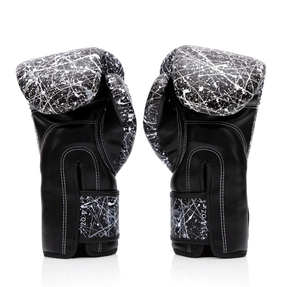A pair of black boxing gloves with white scratch-like paint splatter patterns on the knuckle areas and wrist straps, shown from the back on a white background.