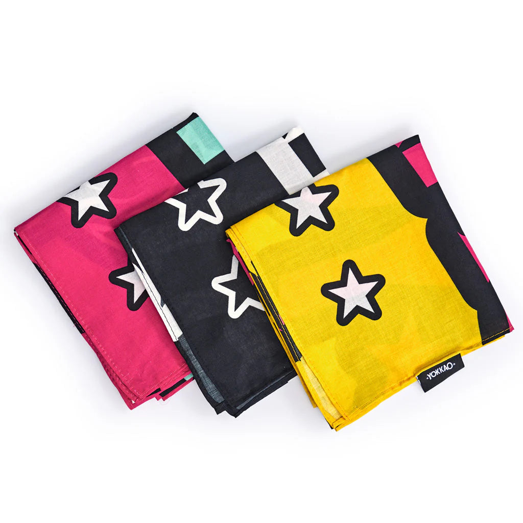 Three folded fabric swatches in pink, black, and yellow with star patterns on a white background.