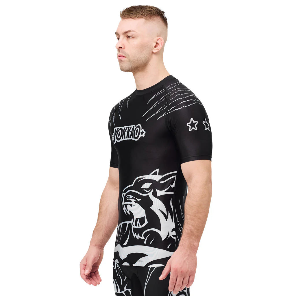 Man wearing a black athletic shirt with white graphics and branding on a white background