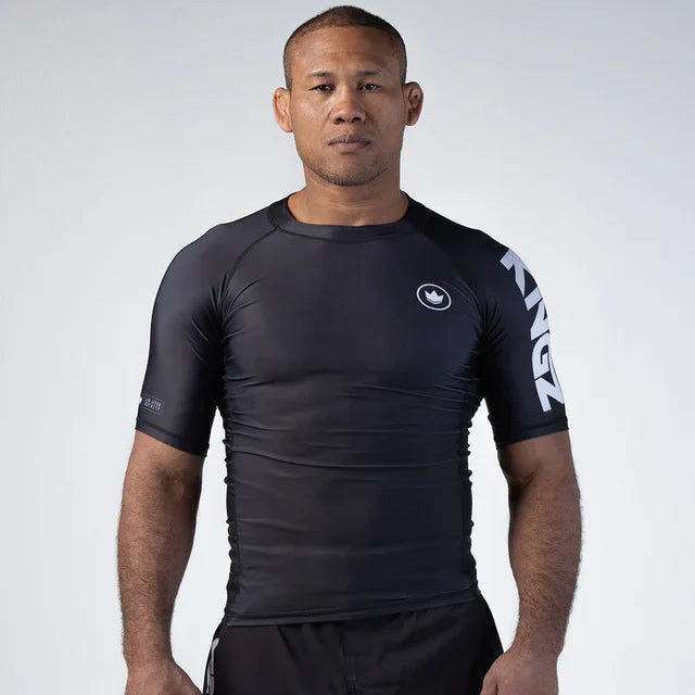 Man wearing a black athletic shirt with branding on a white background