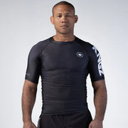 Man wearing a black athletic shirt with branding on a white background