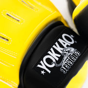 Close-up of yellow boxing gloves with YOKKAO logo on a white background