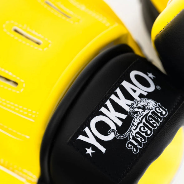 Close-up of yellow boxing gloves with YOKKAO logo on a white background