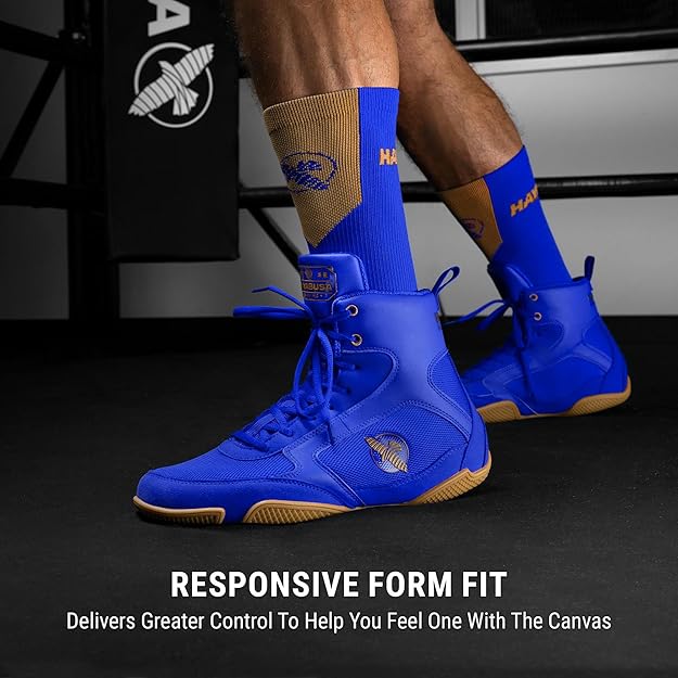 Blue boxing shoes with brown soles worn by a person, on a dark background.