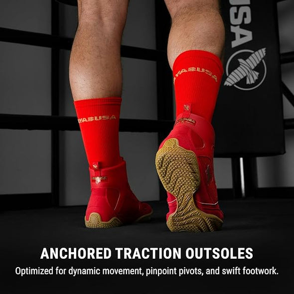 Red athletic shoes with anchored traction outsoles on a dark background, featuring a brand logo.