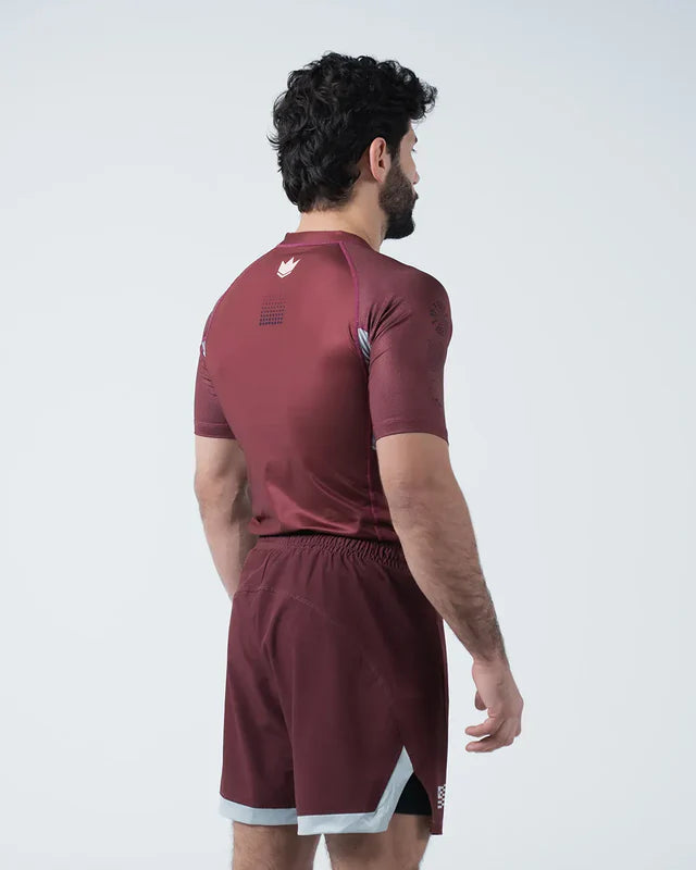 Man wearing a maroon athletic outfit with a white background