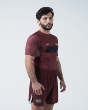 Man wearing a maroon athletic outfit with black accents on a white background