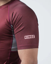 Maroon athletic shirt with 'KINGZ' logo on sleeve against a light gray background