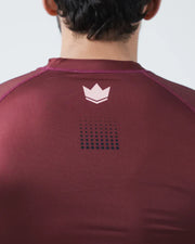 Maroon athletic shirt with a logo on the back against a plain background