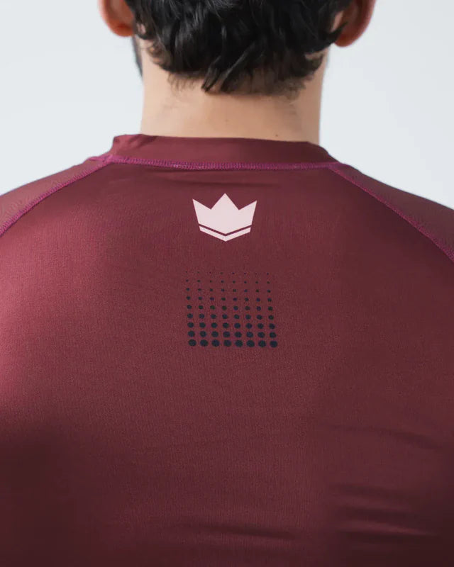 Maroon athletic shirt with a logo on the back against a plain background