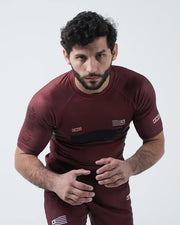 Man wearing a maroon athletic outfit with logos on a white background