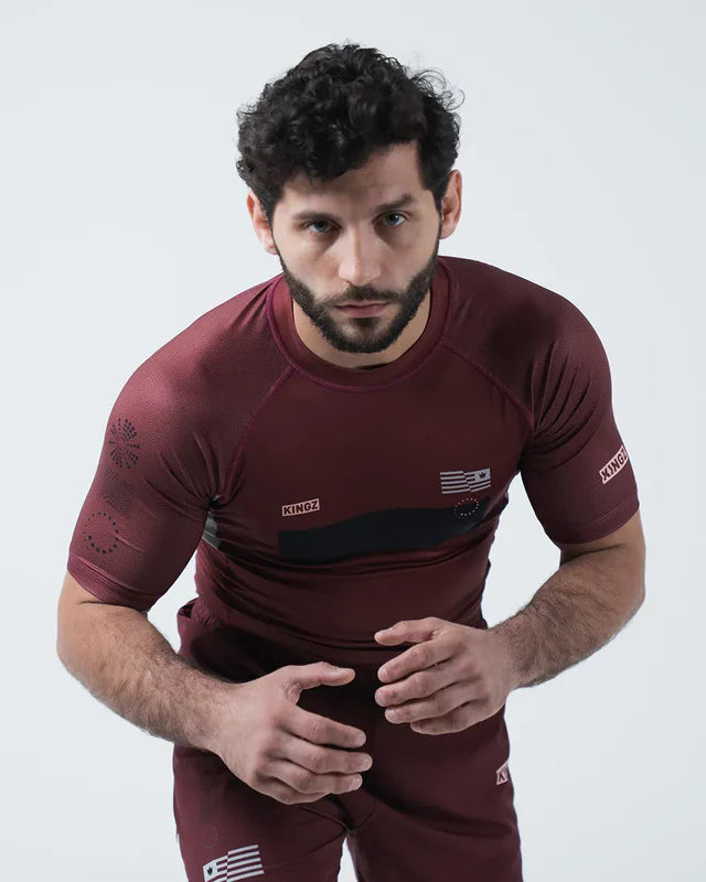 Man wearing a maroon athletic outfit with logos on a white background