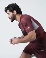 Man wearing a maroon athletic outfit with 'KINZ' branding on a white background