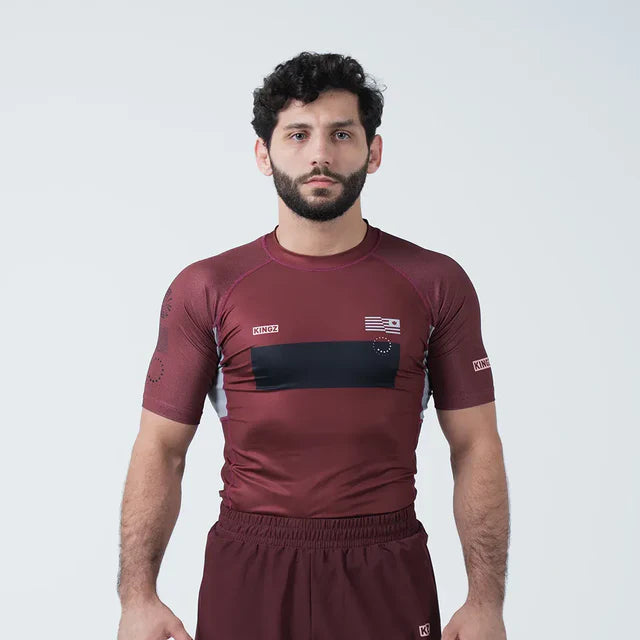Man wearing a maroon athletic outfit with black accents on a white background