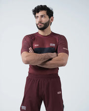 Man wearing a maroon athletic outfit with logos on a white background