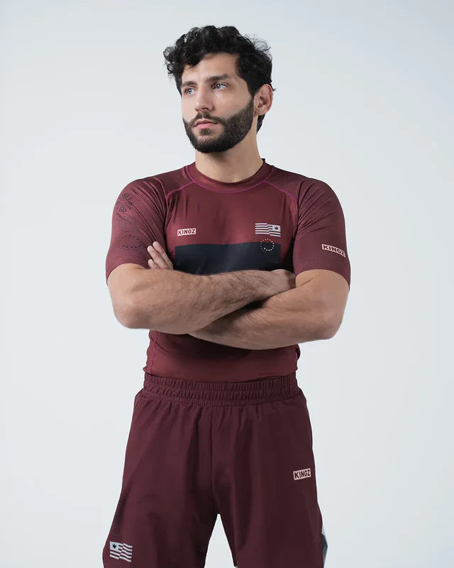 Man wearing a maroon athletic outfit with logos on a white background
