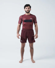 Man wearing a maroon athletic outfit with black accents on a white background