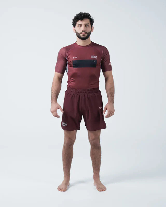 Man wearing a maroon athletic outfit with black accents on a white background