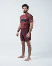 Man wearing a maroon athletic outfit with black accents on a white background