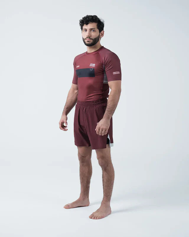 Man wearing a maroon athletic outfit with black accents on a white background