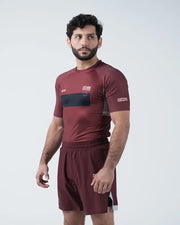 Man wearing a maroon athletic outfit with visible branding on a white background