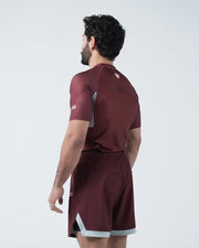 Man wearing a maroon athletic outfit with a visible brand logo on a white background