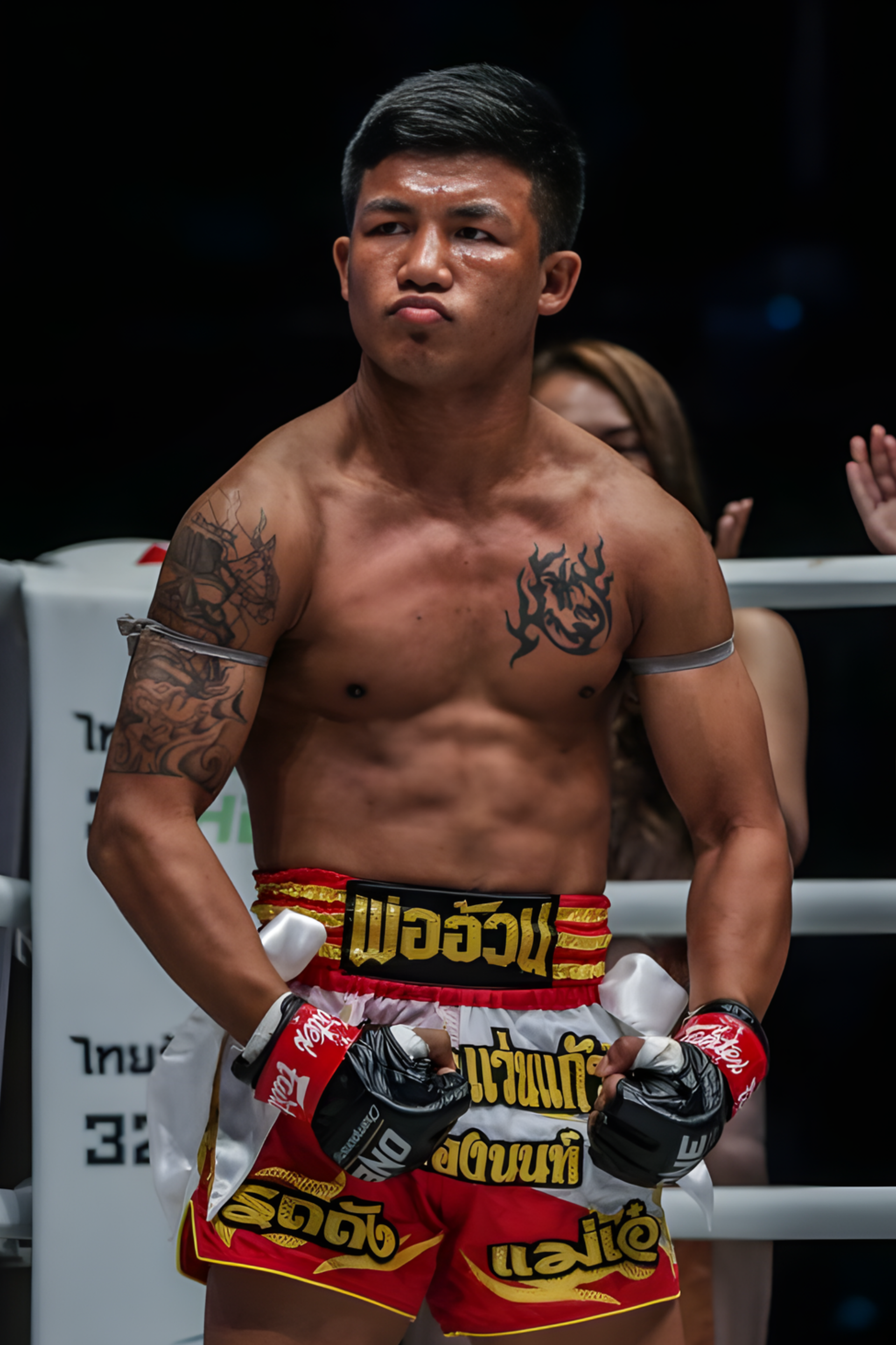 Athlete in red and yellow shorts with gloves, standing in a boxing ring.