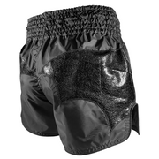 Black athletic shorts with shiny panels on a gray background