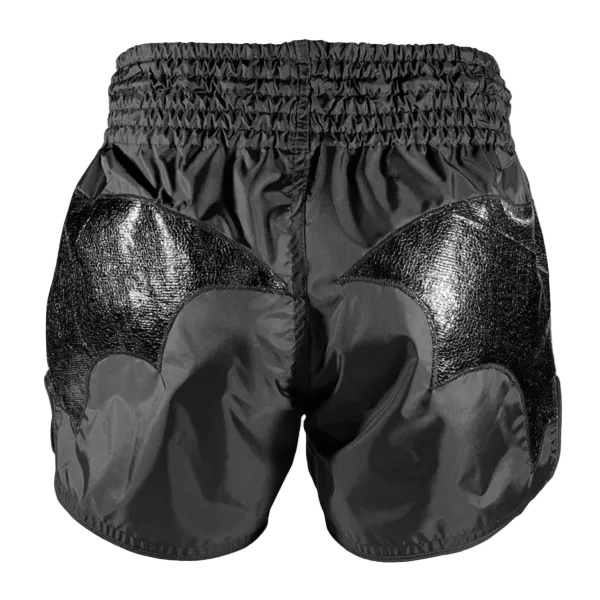 Black boxing shorts with shiny panels on a gray background
