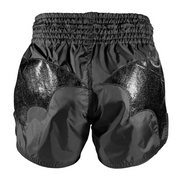 Black boxing shorts with shiny panels on a gray background
