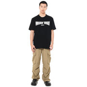 Person wearing a black 'Muay Thai' t-shirt and beige cargo pants on a white background