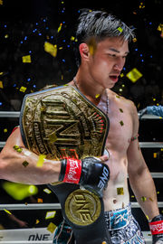 Athlete holding a championship belt with confetti in the background