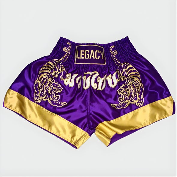 Purple and gold shorts with tiger designs and 'Legacy' branding on a light gray background