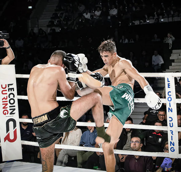 Two boxers in a boxing ring with spectators watching.