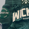 Green boxing shorts with 'Wicked One' branding on a gray background