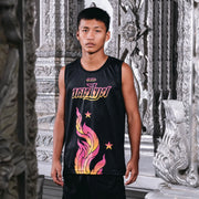 Person wearing a black sleeveless shirt with colorful designs and text, standing in an ornate indoor setting.