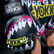 Black boxing gloves with shark design and 'Yokkao' branding on a dark background