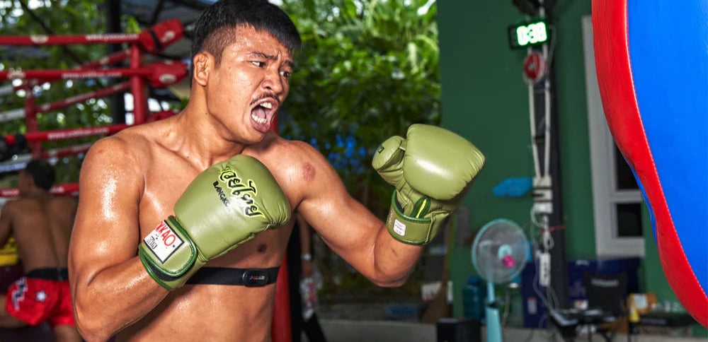 Boxer in green shorts and gloves in a boxing ring with a blurred background