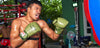 Boxer in green shorts and gloves in a boxing ring with a blurred background