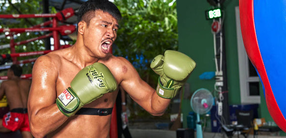 Boxer in green shorts and gloves in a boxing ring with a blurred background