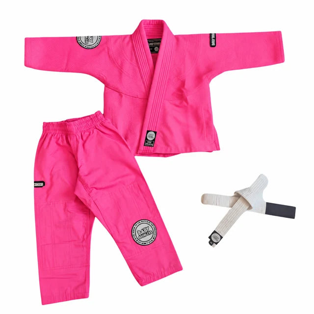 A bright pink martial arts uniform set laid out on a white background, including a gi jacket, matching pants, and a white belt with a black tip.