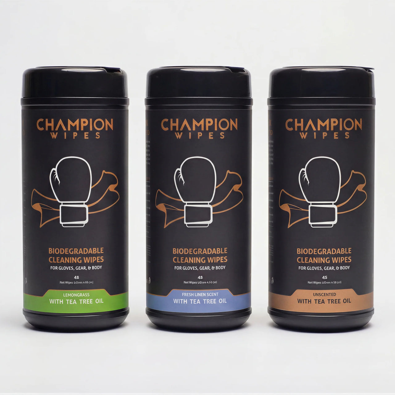 Three black cylindrical canisters of Champion Wipes biodegradable cleaning wipes arranged side by side on a light gray background. The left canister is labeled 'Lemon草ase with Tea Tree Oil' with a green band, the middle is 'Fresh Lemonade with Tea Tree Oil' with a blue band, and the right is 'Unscented with Tea Tree Oil' with a brown band.