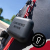 Black carabiner with 'CONFIDENCE WITHIN' text attached to a bag outdoors.