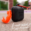 Black case with red straps and 'Confidence Within' text on a blurred outdoor background