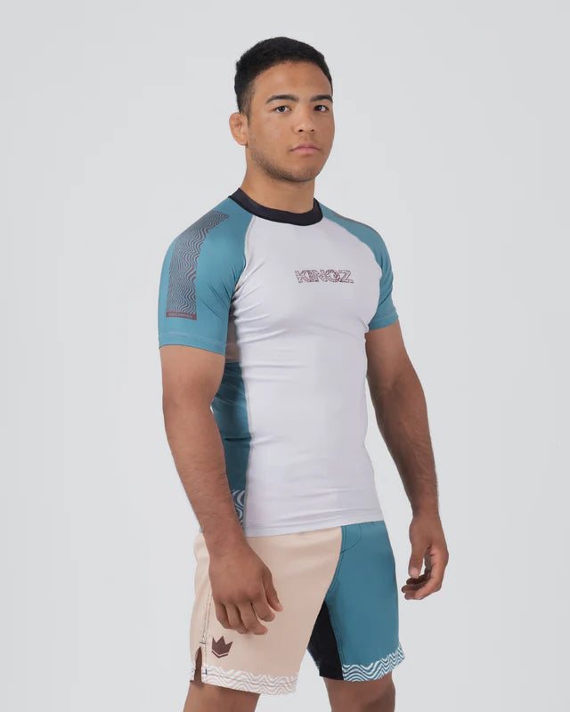 Man wearing a white and blue athletic shirt with matching shorts on a gray background