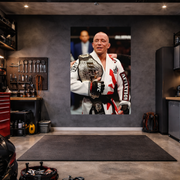 Man holding a championship belt in a garage setting with tools and equipment.