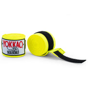 Yellow boxing hand wraps with black velcro strap and Yokkao branding on a white background