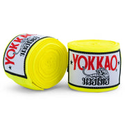 Two rolls of yellow Yokkao hand wraps on a white background