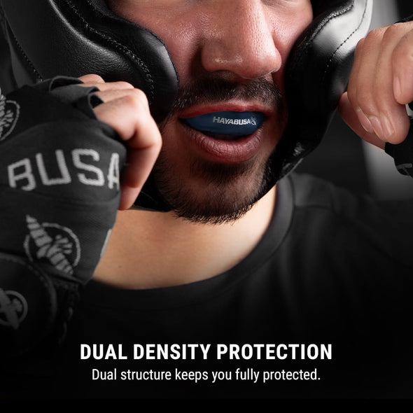 Person wearing boxing gloves and headgear with 'HAYABUSA' branding, emphasizing dual density protection.