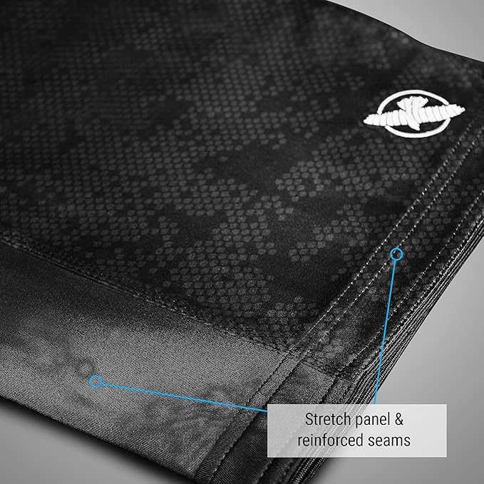 Close-up of black fabric with a pattern and a brand logo, highlighting stretch panel and reinforced seams.
